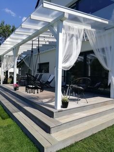 a white pergolan covered patio with lounge chairs and table on the grass area