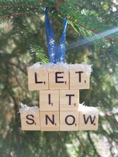 a wooden block ornament hanging from a tree with let it snow written on it