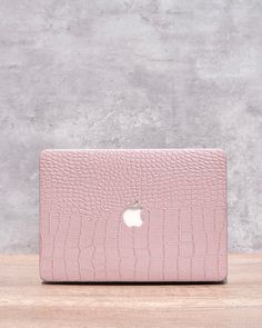 an apple macbook air case in pink crocd leather on a wooden table