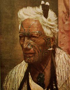 an old native american man with white hair and tattoos on his face, looking at the camera