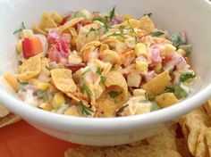 a white bowl filled with corn salad next to tortilla chips