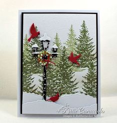 a christmas card with red birds on a street light and evergreen trees in the background