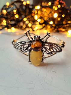 ❤ This handmade amber bee bracelet is an exquisite piece of jewelry that beautifully combines the elegance of amber with the charming motif of a bee.  ❤ Each cuff bracelet contains polished cognac, green & butterscotch Baltic amber stones with natural fossils inside, so every bracelet is unique & one of a kind. ❤ In folklore, bees are associated with the harmony of the nation and family, close friendship, and spiritual life. So, a jewelry with a cute bee motif can be a warm & cosy gift for a fri Bee Charm For Bracelet, Amber Bangle Bracelet For Gift, Amber Bangle Jewelry For Gift, Adjustable Amber Bangle Jewelry, Handmade Honey Color Jewelry Gift, Handmade Honey Jewelry For Gift, Handmade Honey-colored Jewelry For Gifts, Close Friendship, Bee Bracelet