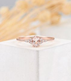 an engagement ring with two diamonds on top and a pink diamond in the middle, sitting on a white box