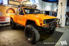 an orange jeep is on display in a showroom