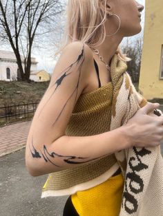 a woman with tattoos on her arms and arm is holding a scarf over her shoulder