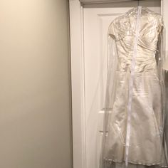 a white dress is wrapped in plastic on a hanger next to a door handle