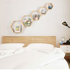 a bed with white sheets and pillows next to a wall mounted shelf on the wall