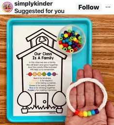 a hand holding a beaded bracelet next to a small tray with beads on it