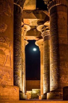 the interior of an ancient egyptian temple at night with columns and carvings on either side