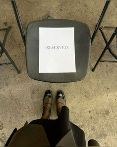 a person sitting on a chair with their feet up in front of a sign that reads reserved