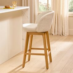 a white counter top sitting next to a wooden bar stool in a room with wood floors