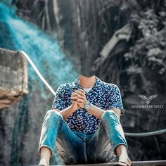 a young man sitting on top of a metal rail next to a waterfall in the woods