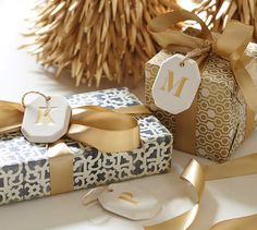 two wrapped presents with gold ribbons and monogrammed tags