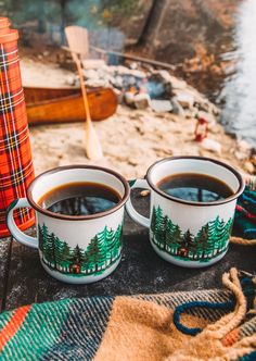 two cups of coffee sitting next to each other on top of a table near the water