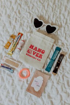 the contents of a travel bag laid out on a bed with sunglasses, toothpaste, and other items