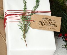 a white present wrapped in brown paper and tied with red twine next to evergreen branches