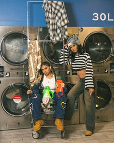 two women are sitting in front of washing machines