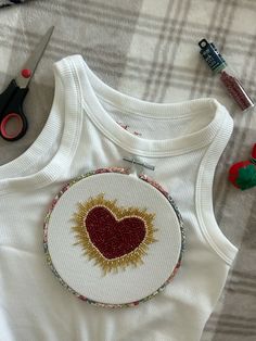 a white shirt with a red heart on it next to scissors and other crafting supplies