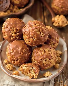 chocolate peanut butter balls on a plate with walnuts in the background and more nuts scattered around them