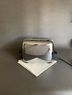 a toaster sitting on top of a table next to a napkin