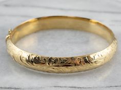 Stunning! The details on this vintage 18 karat gold bangle are simply gorgeous! Intricate botanical designs are engraved in warm yellow gold, covering the entire bracelet. Beautiful on its own or layered with other bracelets this piece is perfect for day or evening wear. Metal: 18K Yellow Gold Width: 11.1 mm Inside Circumference: 7 Inches Marks: "GERMANY 18KO " Stamped Luxury Gold Bracelets With Engraving Option, Luxury Gold Bangle With Jewels, Luxury Elegant Gold Bracelet Engraved, Luxury Gold Bangle Bracelet For Formal Occasions, Luxury Gold Bangle Bracelet For Formal, Affordable Engraved Bangle Bracelets, Elegant Luxury Gold Bangle Bracelet, Luxury Engraved Brass Bracelets, Luxury Brass Bangle Gift