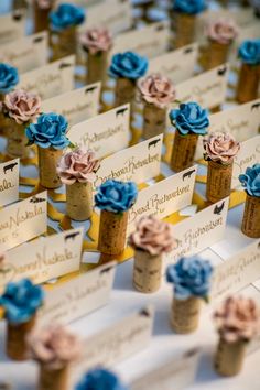 there are many place cards with flowers in them on top of corks that have name tags attached to them