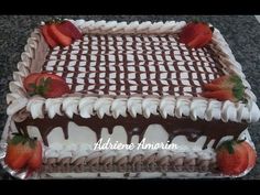 a chocolate cake topped with strawberries on top of a kitchen counter covered in icing