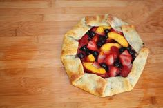 a pie with fruit on it sitting on top of a wooden table