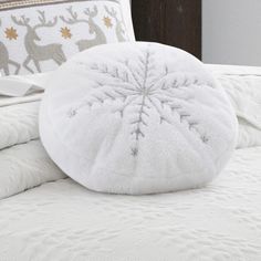 a white bed topped with pillows covered in snowflakes and reindeers on it