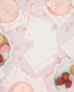 a table topped with plates filled with pastries and strawberries on top of it