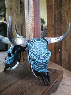 a cow skull with blue and white designs on it's head sitting on a wooden table