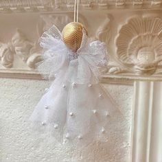 an angel ornament hanging from the ceiling in front of a white stucco wall