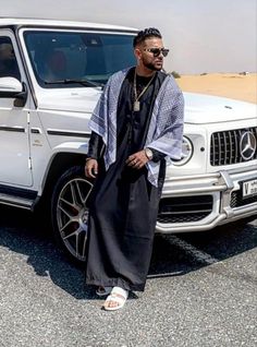 a man standing in front of a white mercedes g63 with his hand on his hip