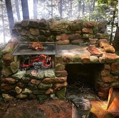 an outdoor fire pit in the woods with rocks and logs around it's edges