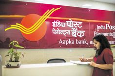 a woman standing at a desk in front of a sign that says india post bank