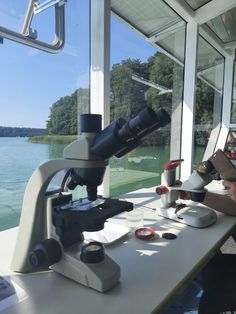 two people looking through microscopes at something in front of them on a boat near the water