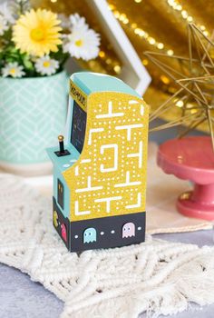 a small toy machine sitting on top of a table next to a potted plant