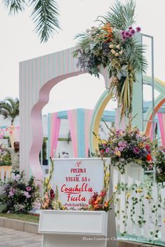 a sign that is sitting in front of some flowers and plants on the side of a road