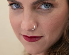 a close up of a woman with blue eyes and nose piercings on her nose