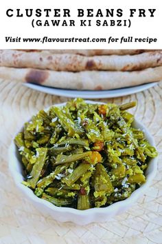 a white bowl filled with green beans next to pita bread on top of a table