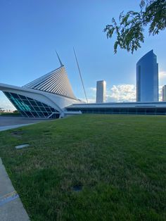 a grassy area in front of a large building with tall buildings on the other side