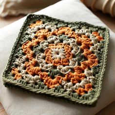 a crocheted square sitting on top of a pillow