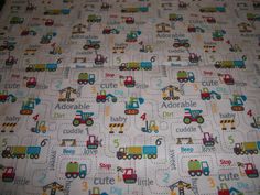 a close up of a baby's bed sheet with trucks and cars on it