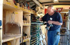 a man working in a garage with tools and equipment on the shelves next to him