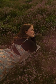 a woman laying in a field of flowers