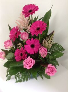 a vase filled with pink flowers and greenery