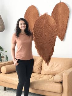 a woman standing in front of a couch with two large leaves on it