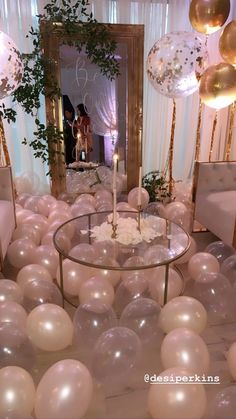 a room filled with balloons and tables covered in white flowers, candles and greenery