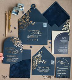 the wedding stationery is set up with gold foil and navy blue paper, which also include matching envelopes